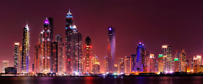 Illuminated modern buildings against sky at night