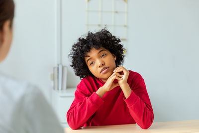 Portrait of young woman looking away against wall