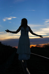 Rear view of silhouette woman standing on field against sky