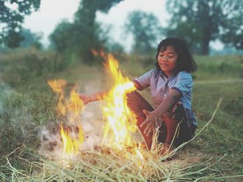 Young man sitting on bonfire at field