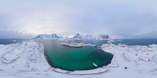 Scenic view of sea by snowcapped mountains against sky