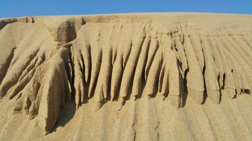 Scenic view of sand dunes at beach against sky