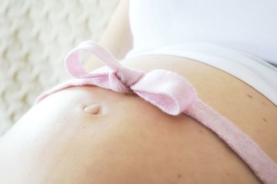 Close-up of pregnant woman with ribbon on abdomen