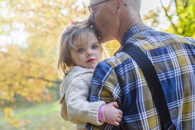 Portrait of cute girl being carried by grandfather at park