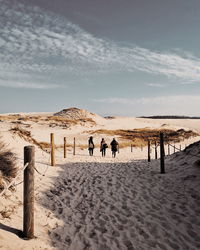 Rear view of women at beach against sky