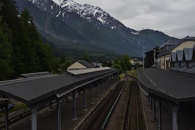 Railway tracks by mountain against sky