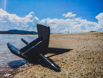 Deck chairs on beach against sky