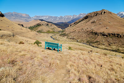 Information sign on field by mountains against clear blue sky