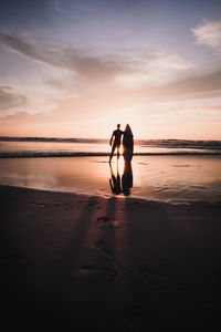 Man standing on beach against sky during sunset