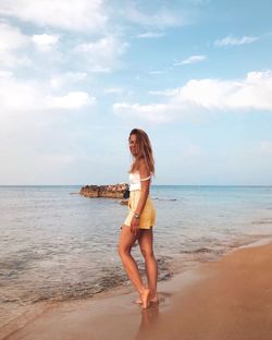 Full length of young woman on beach against sky