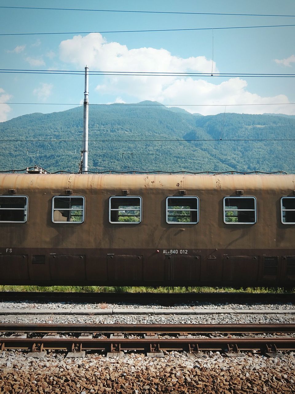 railroad track, rail transportation, transportation, public transportation, railroad station, railroad station platform, train - vehicle, mountain, sky, power line, passenger train, mode of transport, train, travel, electricity pylon, built structure, cable, architecture, public transport, connection