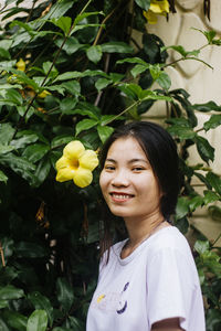 Portrait of smiling young woman standing against plants