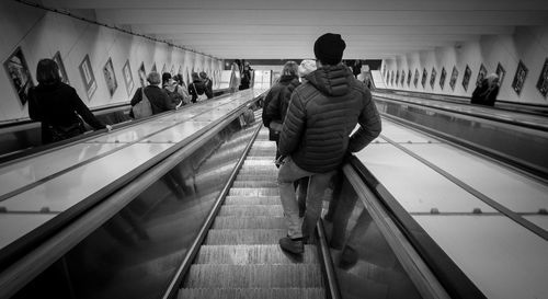 Rear view of people walking on escalator