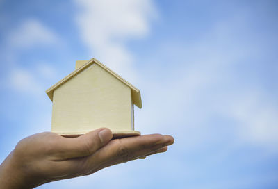 Low section of person holding building against sky