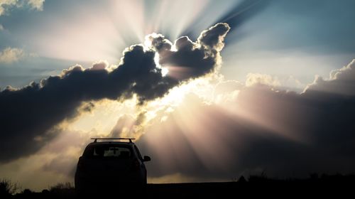 Silhouette car on landscape against sky during sunset