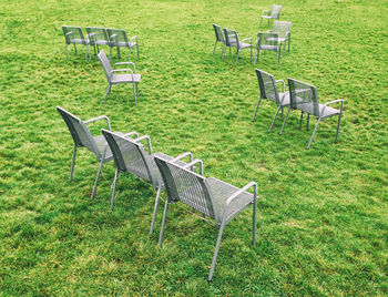 High angle view of empty chairs on grassy field