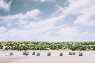 Hooded beach chairs against sky during sunny day