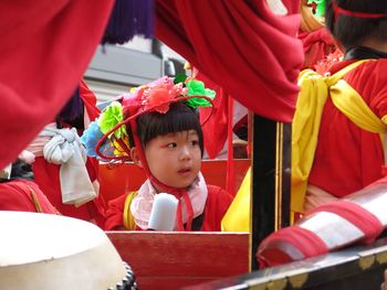 Cute girl looking away while sitting in sedan chair during festival