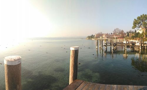 Wooden posts in sea against clear sky