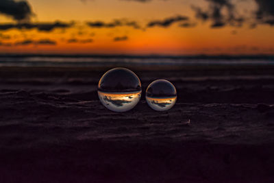 Close-up of lensballs on beach during sunset