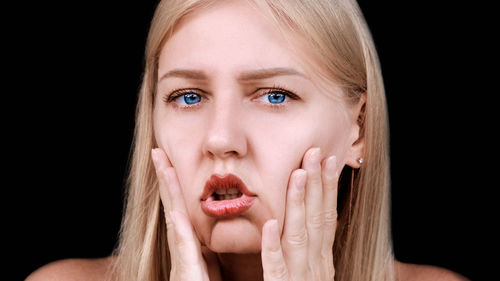 Portrait of young woman against black background