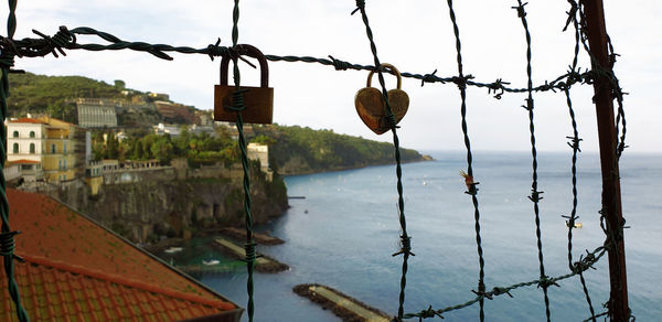 Padlocks hanging on metal fence by river