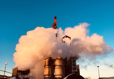 Low angle view of smoke emitting from factory against sky