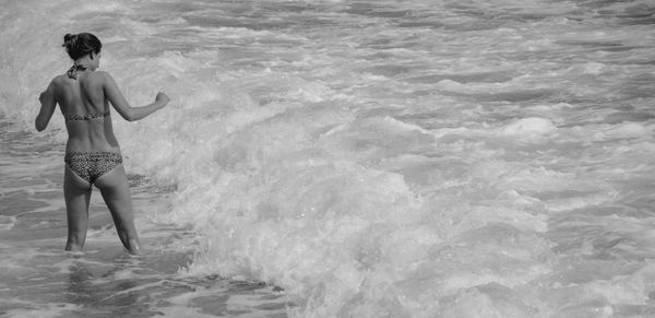 Rear view of woman standing in sea at beach