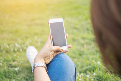Close-up of woman using mobile phone on field