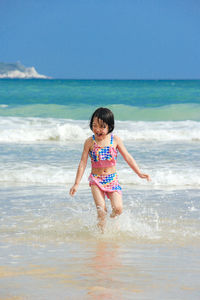 Full length of happy boy on beach against sky