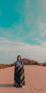 Portrait of young woman sitting on land against sky