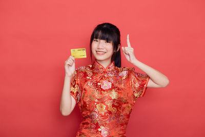Portrait of smiling woman against red background
