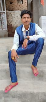 Portrait of young man sitting on sidewalk