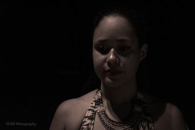 Close-up portrait of a young woman against black background