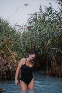 Cheerful woman wearing black swimsuit standing in lake