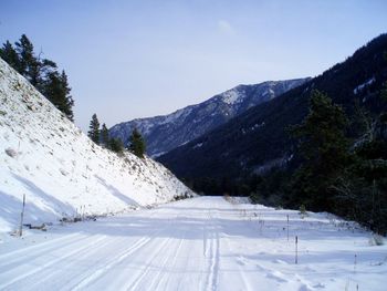 Snow covered road amidst mountains against sky