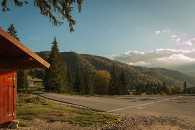 Road amidst trees and landscape against sky