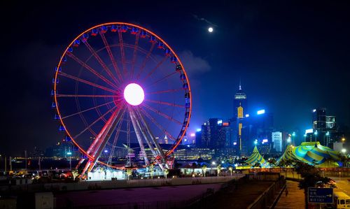 Illuminated ferris wheel against sky at night