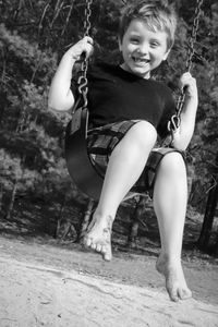 Portrait of smiling boy swinging at park