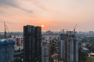 Modern buildings in city against sky during sunset