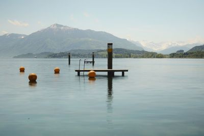 Wooden posts in lake against sky