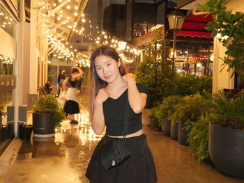 Portrait of young woman standing against christmas tree