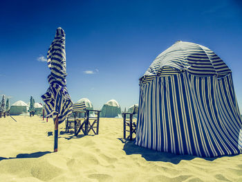 Chairs on beach against clear blue sky