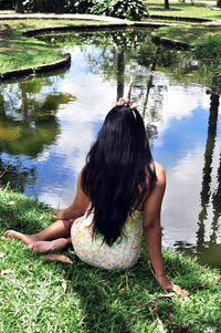 Rear view of woman sitting by lake