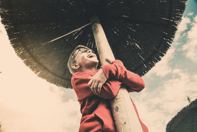 Low angle view of boy embracing parasol against sky