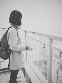 Woman standing in balcony against sky during winter