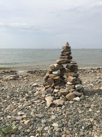 Stack of stones on beach against sky