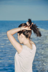 Woman standing by sea against sky