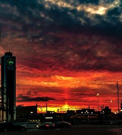 Cars on road against dramatic sky during sunset