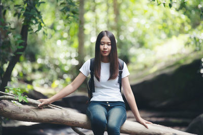 Young woman sitting on tree in forest